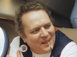 Larry Flynt smiling on a private jet plane with a toothpick in his mouth